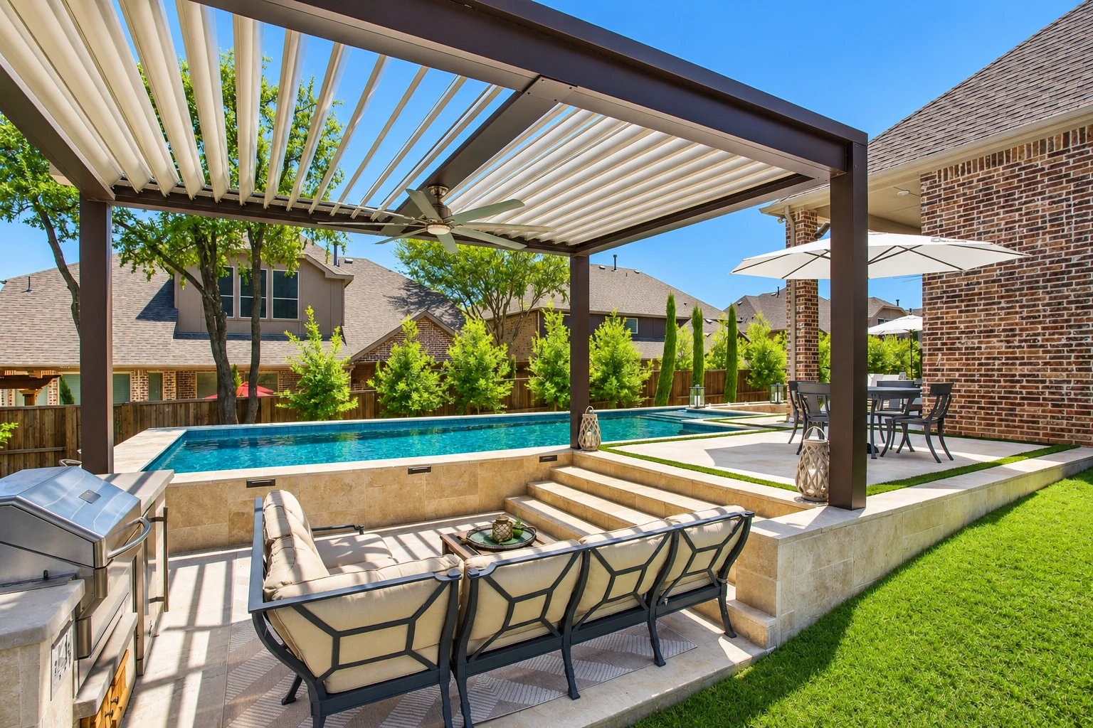 A covered patio enclosure with adjustable white roof slats shelters lounge seating beside a swimming pool.